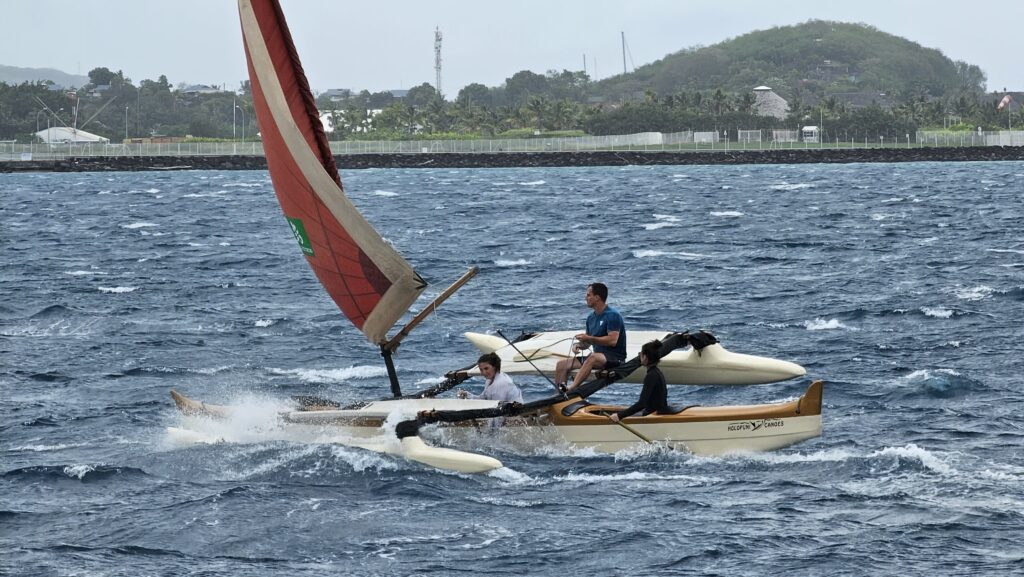 Local Tahitians enjoy the wind, steering a trimaran with their paddles